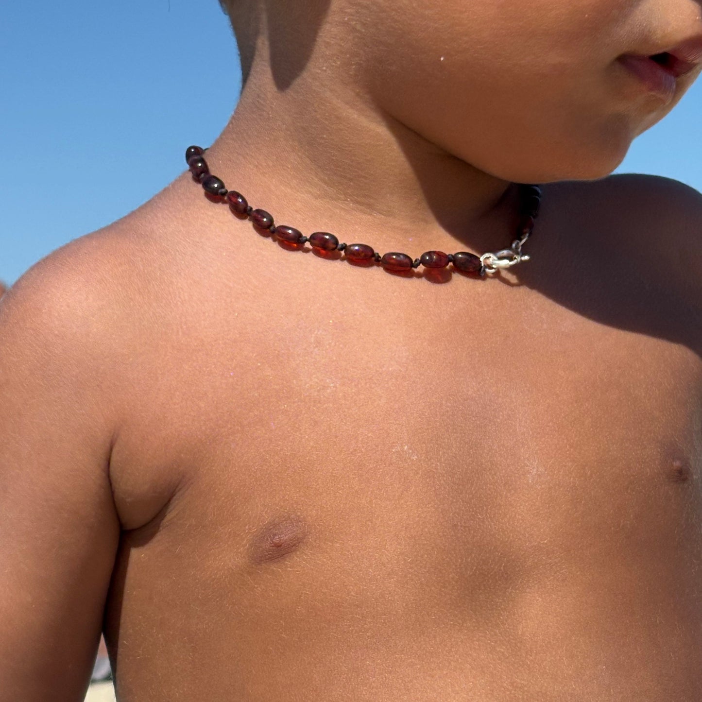 Colar oval em âmbar com fecho prateado para bebé e criança.